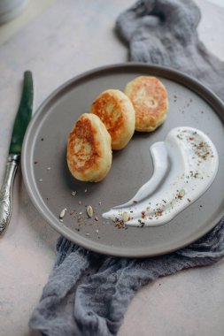 Üç kızarmış patates kroketi ile et, soslu yuvarlak bir tabakta servis edilir.