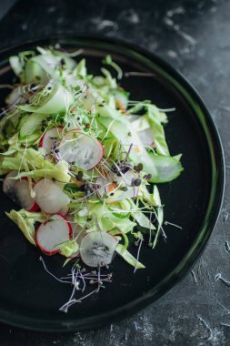 Taze sebze salatası ve siyah tabakta mikro sebzeler.