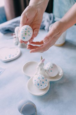 Mavi çiçekle boyanmış paskalya yumurtası kadınların elinde.