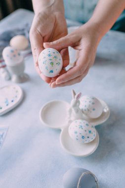 Mavi çiçekle boyanmış paskalya yumurtası kadınların elinde.