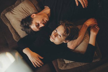 Baba oğul siyah elbiseli bir ailenin içinde yan yana yatıyorlar.