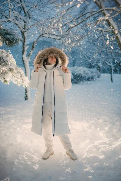 Karlı bir arka planda, alacakaranlıkta beyaz elbiseli bir kadın.