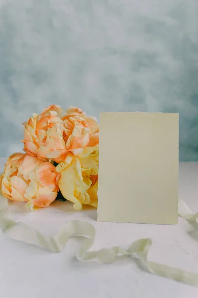 Postcard mockup on the background of peonies flowers on a light background