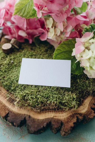 business card mockup in nature style, white paper on green moss and wood cut