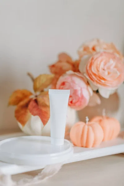 mockup of a tube of cosmetic for the skin, on the background of flowers and candles