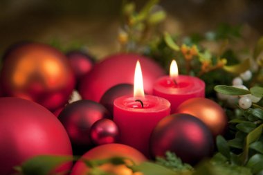 Kırmızı ve altın Noel süslemesi Ökse otu çelenginde mum ışığıyla