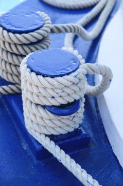 White ropes tied to blue wooden poles on deck of a sailing boat