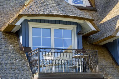 Sazlık sazdan bir evin çatısında mobilyaları olan bir balkon.