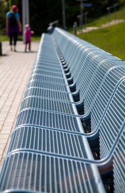 Arka planda bulanık ve tanınmayan insanların yürüdüğü uzun metal bir bank