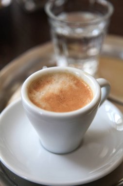Beyaz porselen bardakta espresso ve bir bardak su.