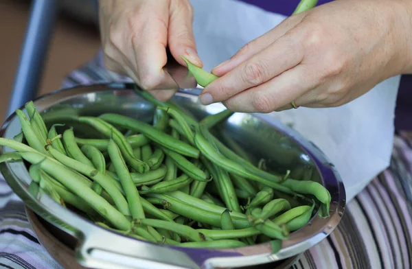 Hands preparing green beans for cooking