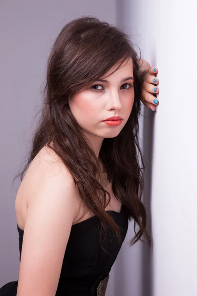 Krásná mladá žena, při pohledu na fotoaparát, proti zdi — Stock fotografie