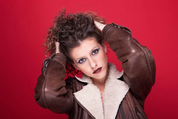 Mulher jovem e bonita, com cabelo encaracolado, segurando seu cabelo com um casaco de inverno, em vermelho — Fotografia de Stock