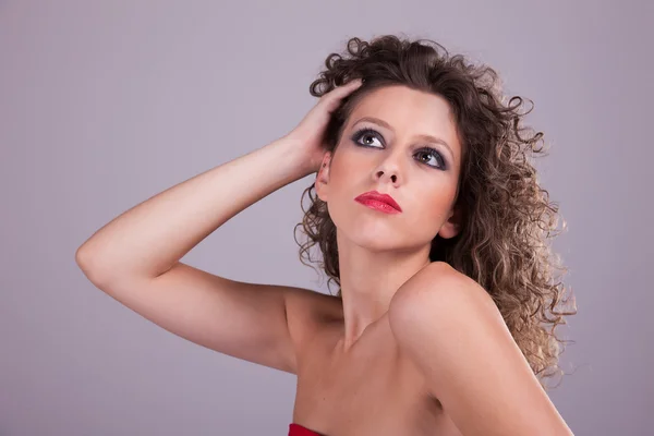 Hermosa mujer con el pelo rizado, sosteniendo el cabello — Foto de Stock