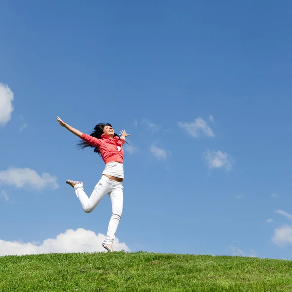 Mooie jonge vrouw springen op groen gras — Stockfoto