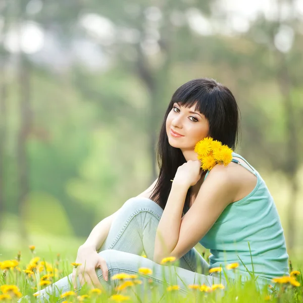 Leuke vrouw in het park met paardebloemen — Stockfoto