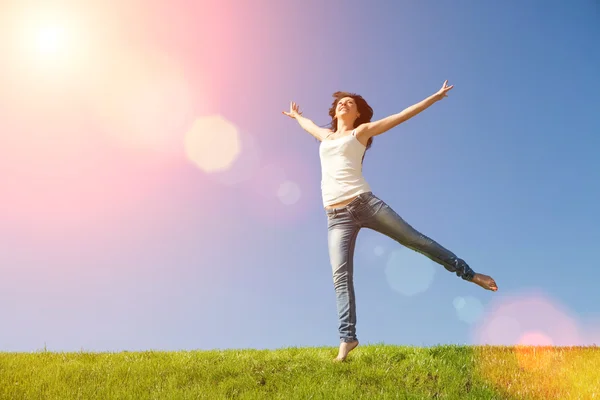 Pretty young woman jumping on green grass — Stock Photo, Image