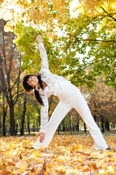 Vakker kvinne som gjør yogaøvelser i høstparken – stockfoto