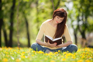 genç kadın çiçeklerle parkta bir kitap okuma