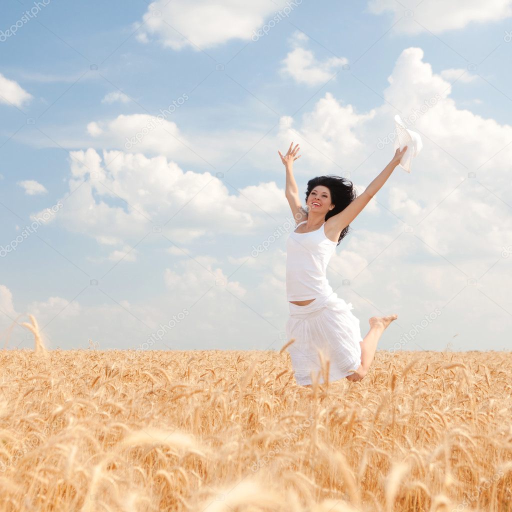 Happy woman jumping in golden wheat