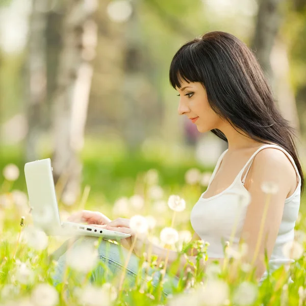 Aranyos nő fehér laptop a parkban pitypang — Stock Fotó