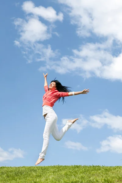 Hübsche junge Frau springt auf grünem Gras — Stockfoto