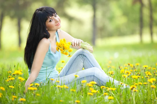 Niedliche Frau im Park mit Löwenzahn — Stockfoto