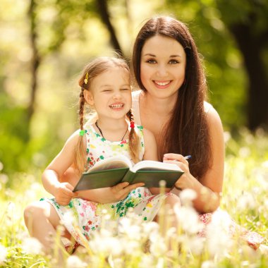 Anne ve kızı parkta çim üzerinde çizim