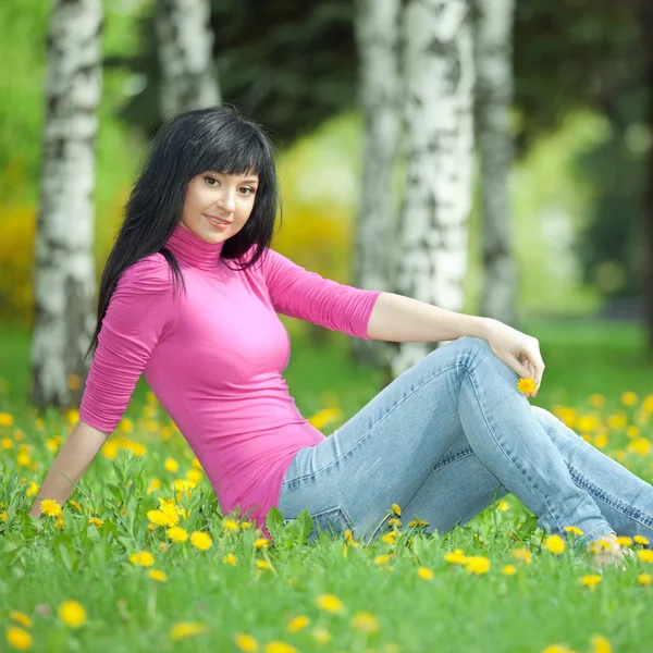 Leuke vrouw in het park met paardebloemen — Stockfoto