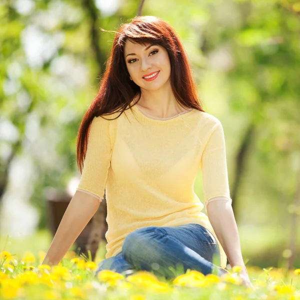 Jonge redhead vrouw in het park met bloemen — Stockfoto