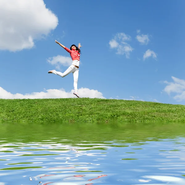 Pretty young woman jumping on green grass — Stock Photo, Image