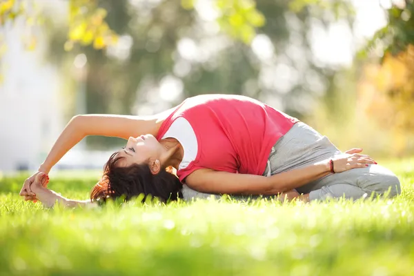 Parkta yoga egzersizi yapan güzel bir kadın. — Stok fotoğraf