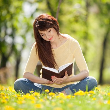 genç kadın çiçeklerle parkta bir kitap okuma