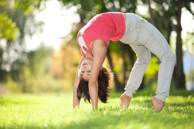 Parkta yoga egzersizi yapan güzel bir kadın.