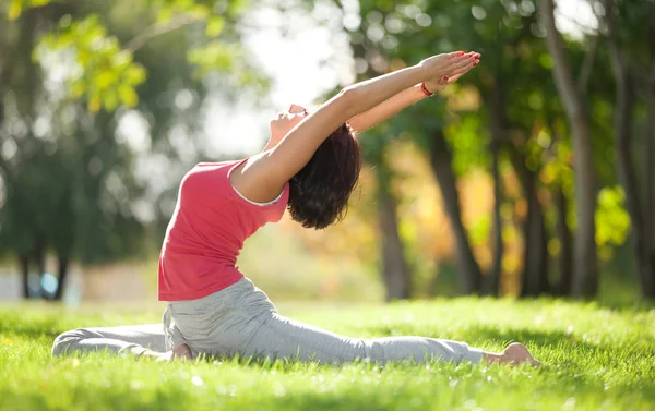 Mulher bonita fazendo exercícios de ioga no parque — Fotografia de Stock