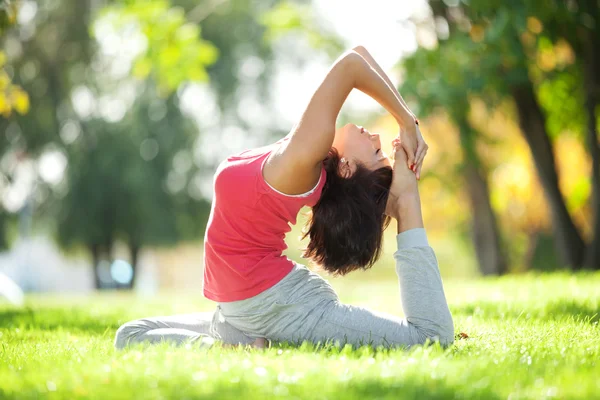 Bella donna che fa esercizi di yoga nel parco — Foto Stock