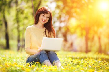 sevimli kadın karahindiba parkta beyaz dizüstü bilgisayar ile