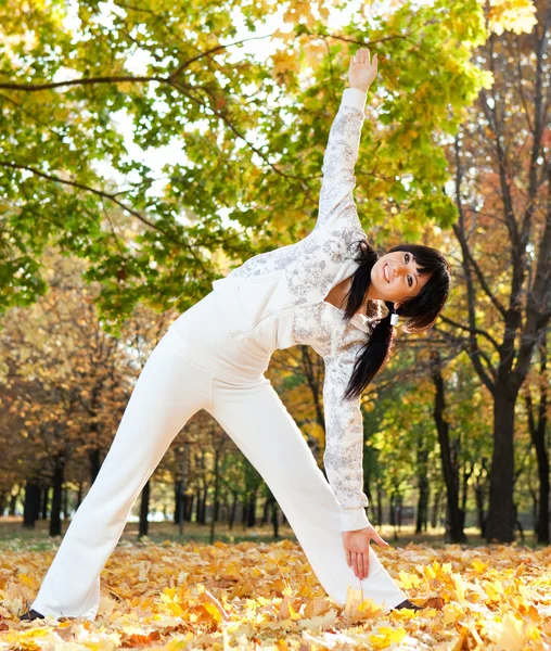 Hezká žena, která dělá cvičení jógy v podzimním parku — Stock fotografie