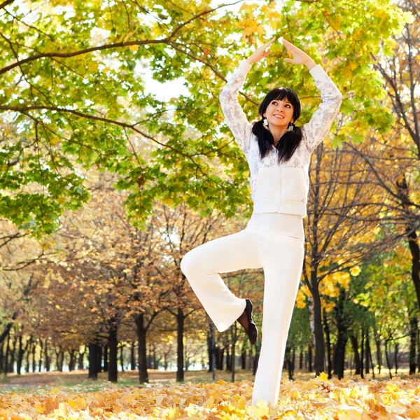 Güzel bir kadın yoga egzersizleri sonbahar Park yapıyor — Stok fotoğraf