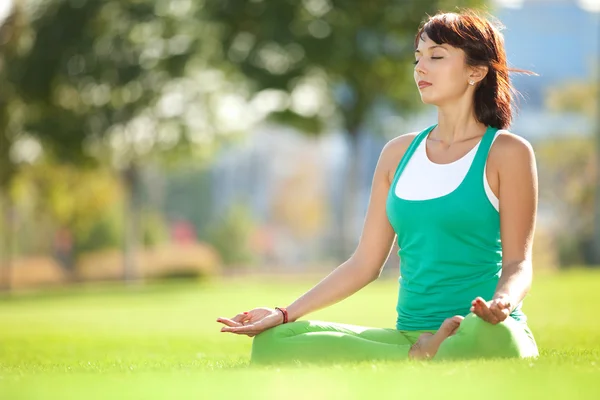 Parkta yoga egzersizi yapan güzel bir kadın.