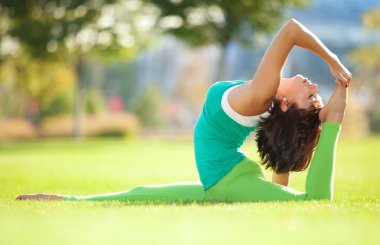 Parkta yoga egzersizi yapan güzel bir kadın.