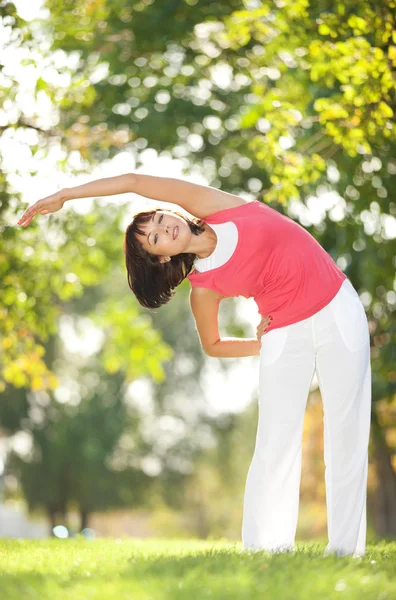 Parkta yoga egzersizi yapan güzel bir kadın. — Stok fotoğraf