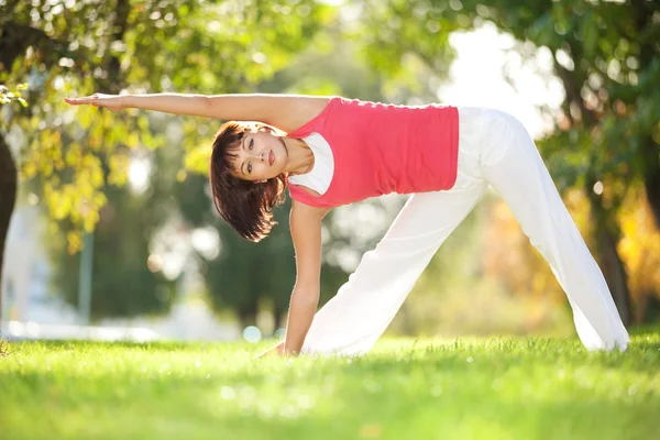 Hübsche Frau macht Yoga-Übungen im Park — Stockfoto