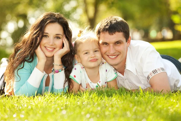 Lycklig mor, far och dotter i parken Royaltyfria Stockbilder