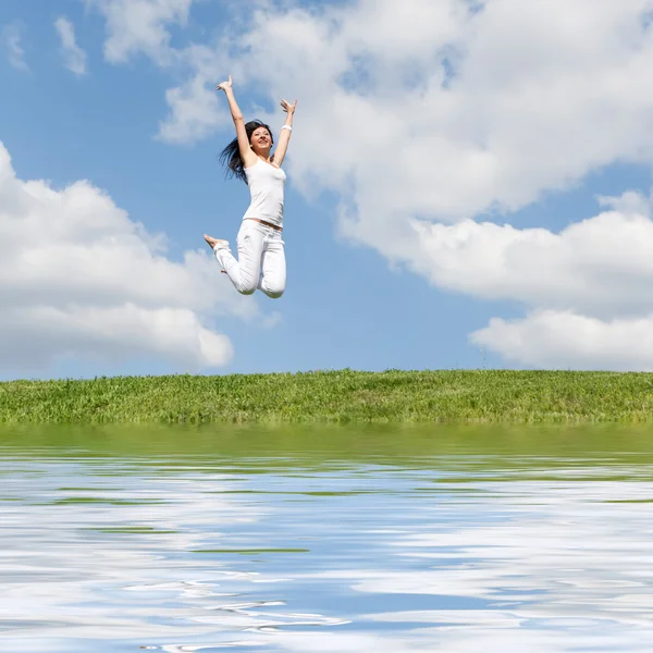 Pretty young woman jumping on green grass — Stock Photo, Image