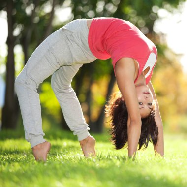 Parkta yoga egzersizi yapan güzel bir kadın.