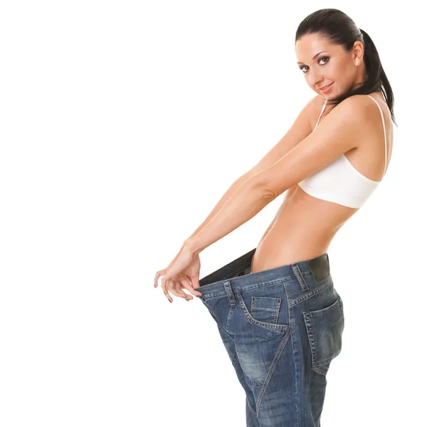 Pretty woman shows her weight loss by wearing an old jeans, isol — Stock Photo, Image