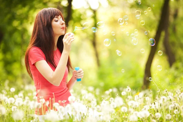 Mulher feliz soprando bolhas no parque — Fotografia de Stock