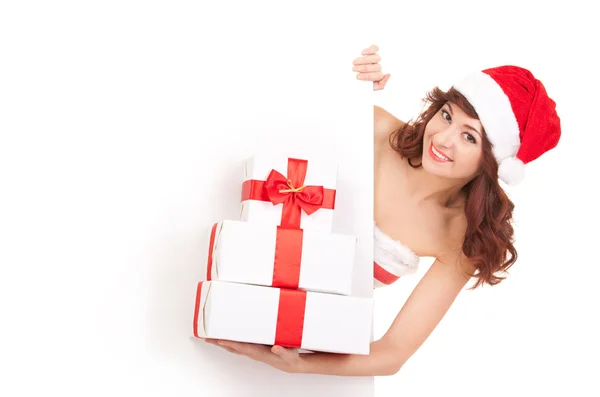 Santa mujer con cajas de regalo mirando el tablero blanco en blanco — Foto de Stock