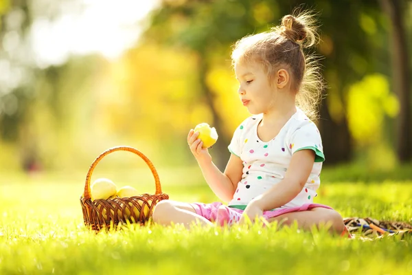 Söt liten flicka äta äpple i parken — Stockfoto
